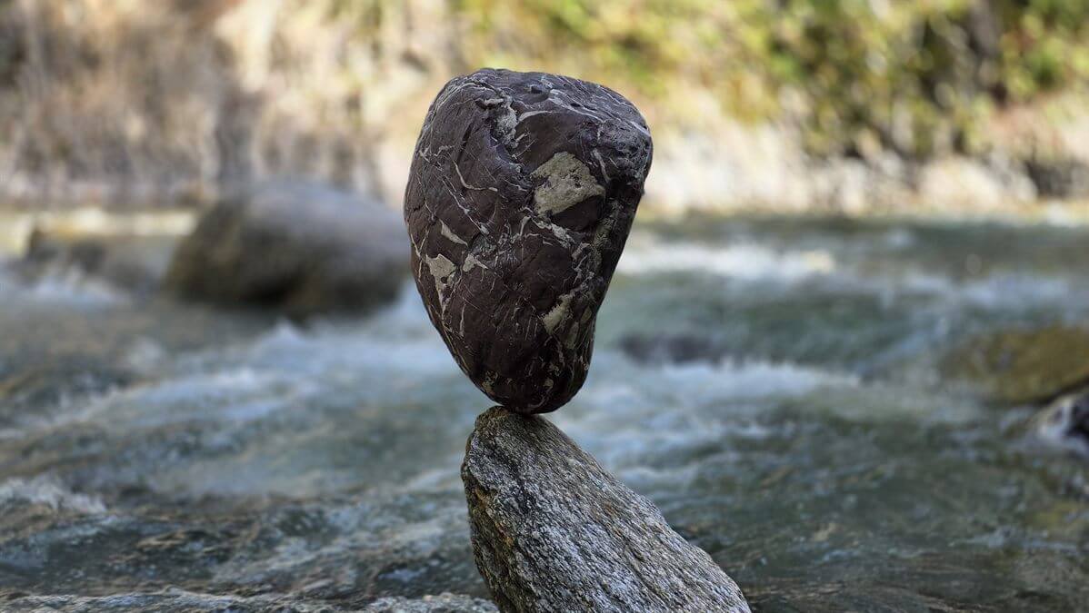 Balancierter Stein auf einem weiteren Stein im fließenden Wasser
